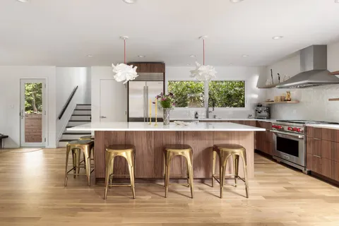 a kitchen with stainless steel appliances granite countertop a stove a sink dishwasher a dining table and chairs with wooden floor