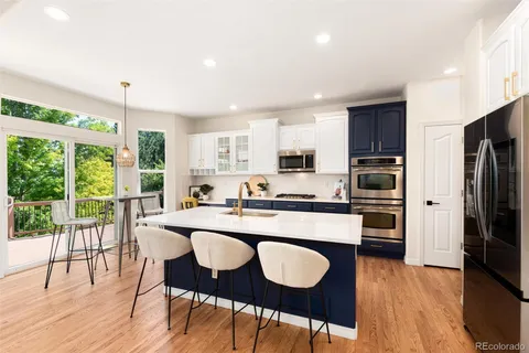 a kitchen with stainless steel appliances granite countertop a sink a stove a refrigerator cabinets and chairs