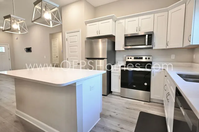 a kitchen with stainless steel appliances a sink a stove a microwave and cabinets