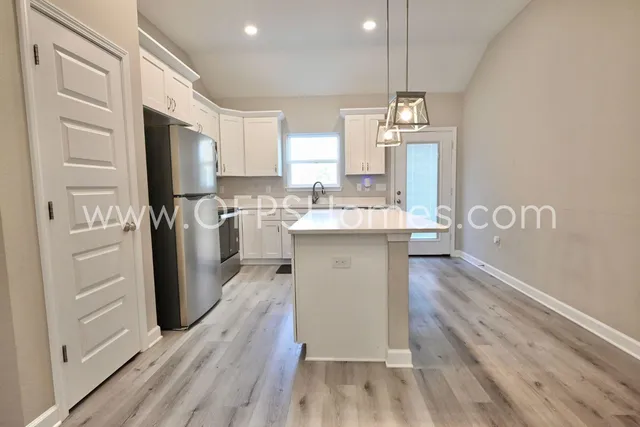 a kitchen with kitchen island a sink a stove cabinets and wooden floor