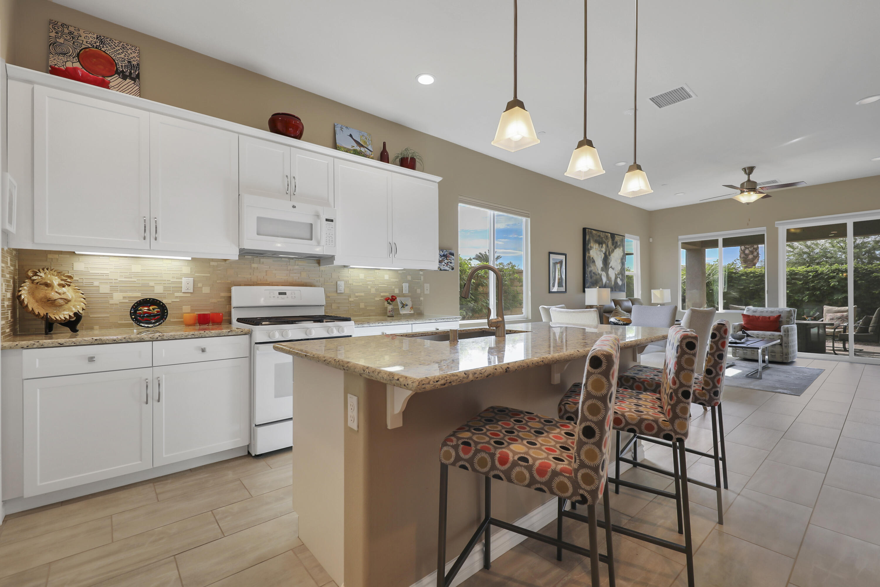 85685 Treviso Drive Indio, CA 92203 - Photo 12 of 32 a kitchen with stainless steel appliances kitchen island granite countertop a table chairs sink and cabinets