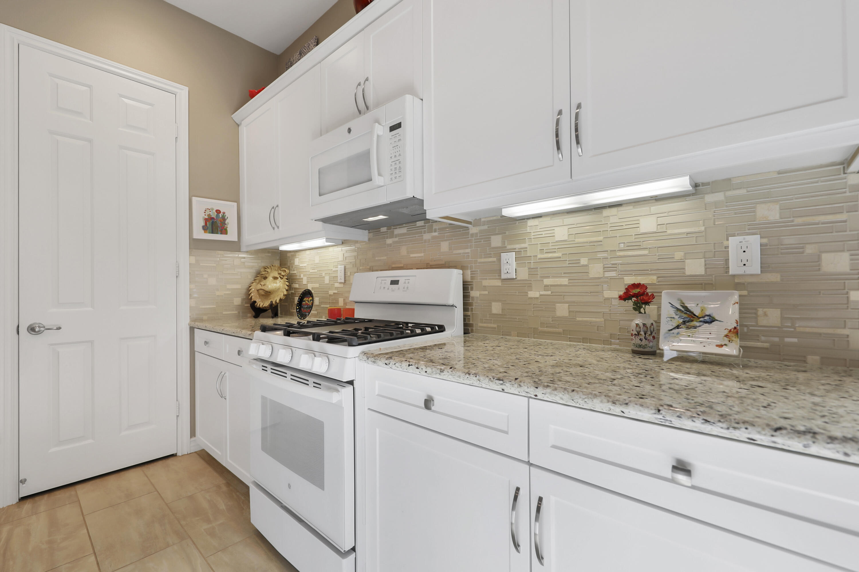 85685 Treviso Drive Indio, CA 92203 - Photo 13 of 32 a kitchen with stainless steel appliances granite countertop a stove and white cabinets