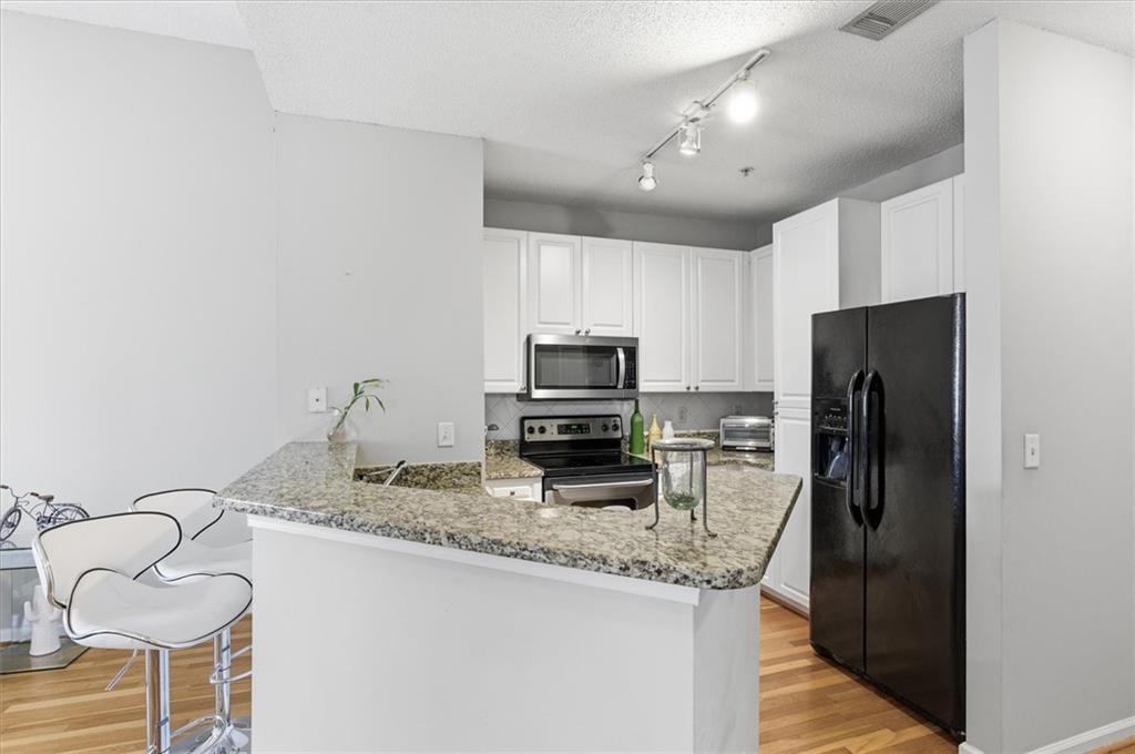 10 Perimeter Summit Boulevard, Unit 2410 Atlanta, GA 30319 - Photo 11 of 31 a kitchen with granite countertop kitchen island a refrigerator and a stove top oven
