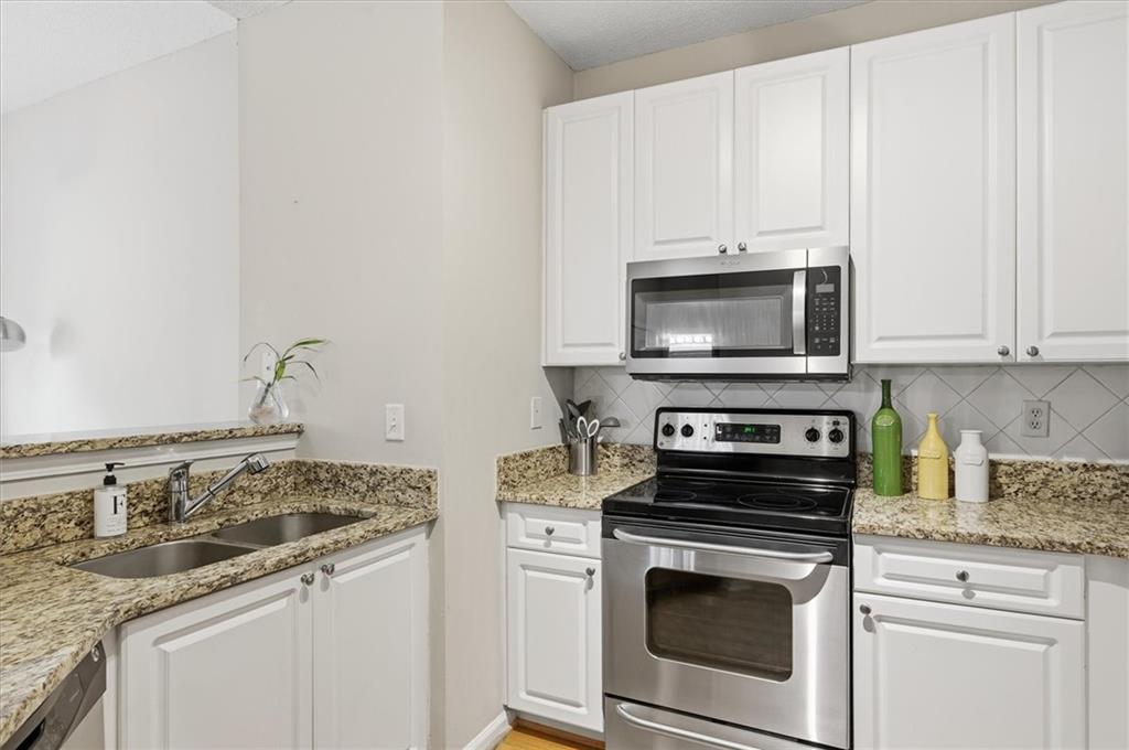 10 Perimeter Summit Boulevard, Unit 2410 Atlanta, GA 30319 - Photo 13 of 31 a kitchen with granite countertop white cabinets and stainless steel appliances