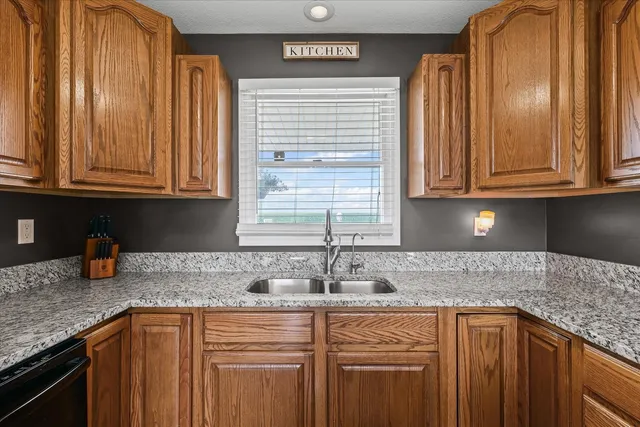 a kitchen with granite countertop stainless steel appliances a sink window and cabinets