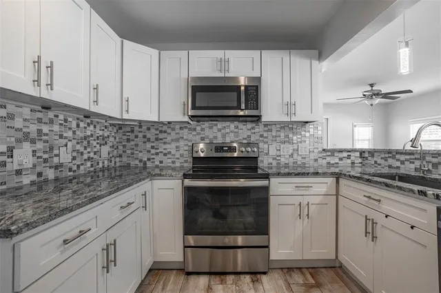 a kitchen with white cabinets and appliances