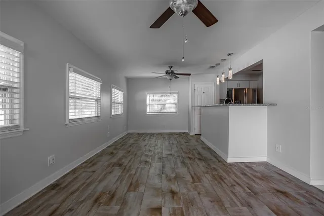 a view of empty room with wooden floor and ceiling fan