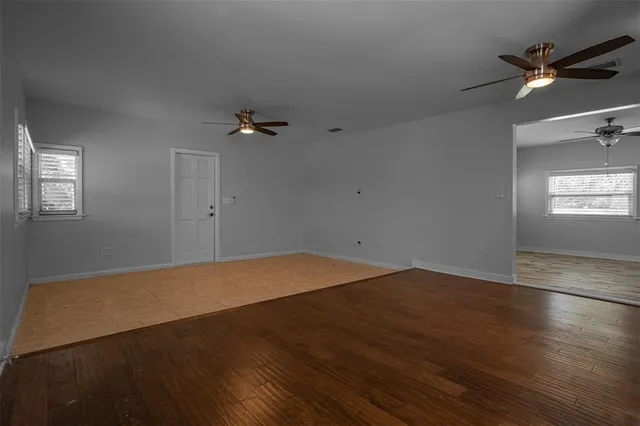 an empty room with a ceiling fan and window