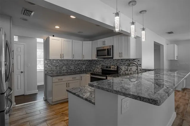a kitchen with kitchen island granite countertop a sink cabinets and stainless steel appliances