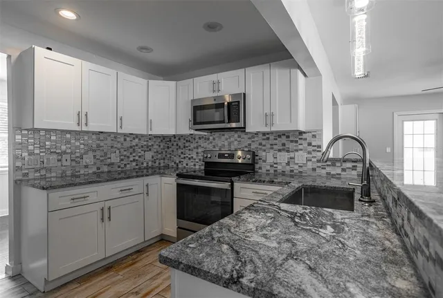 a kitchen with stainless steel appliances granite countertop a stove sink microwave and cabinets
