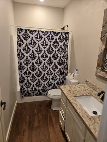 a bathroom with a granite countertop toilet a sink and a mirror