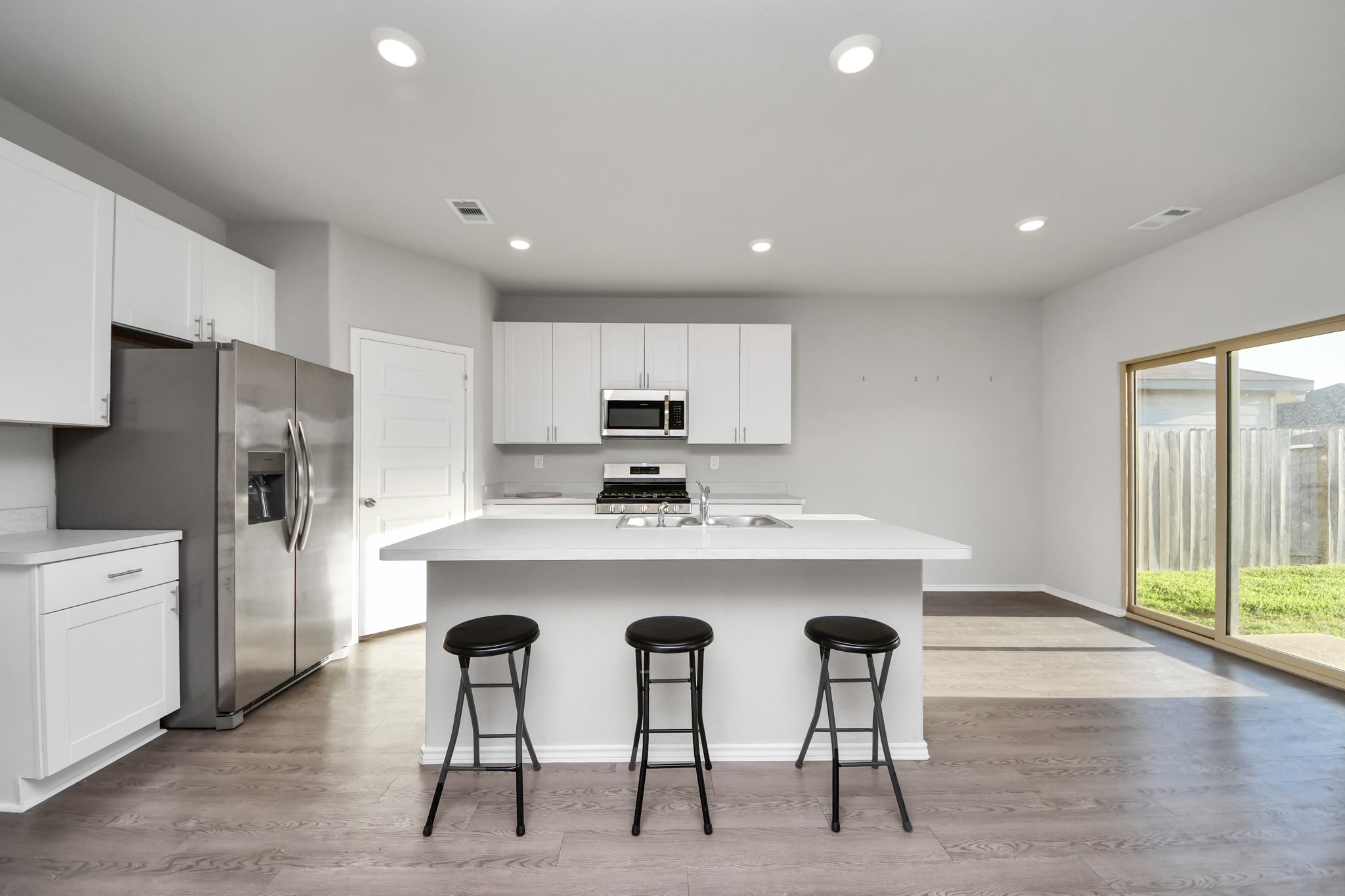 21738 Rustic River Ranch Avenue Waller, TX 77484 - Photo 4 of 24 Bright, open-concept kitchen filled with natural light, featuring a spacious island, sleek white cabinetry, and stainless-steel appliance - perfect for everyday living and entertaining.