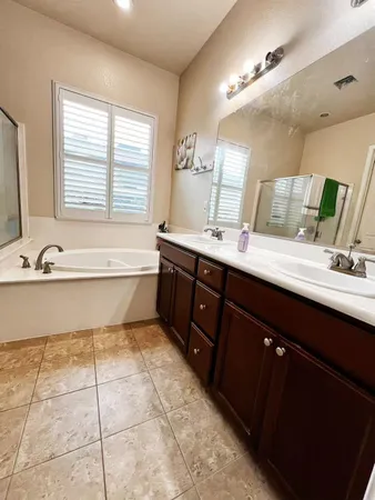 a spacious bathroom with a tub sink and mirror