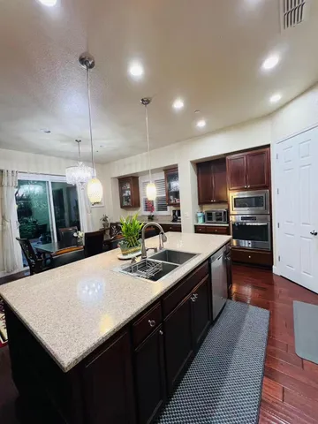 a kitchen with stainless steel appliances granite countertop a sink a stove and a wooden floors