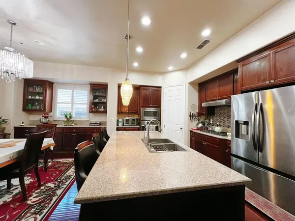 a large kitchen with kitchen island a large counter top stainless steel appliances and cabinets