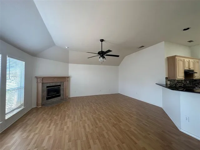 an empty room with windows fireplace and wooden floor
