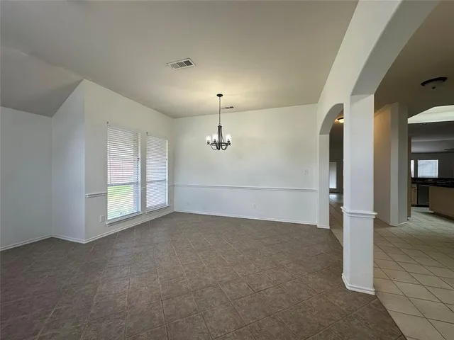 an empty room with chandelier fan and windows