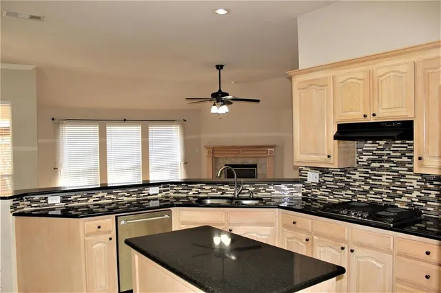 a kitchen with granite countertop a sink a stove and cabinets