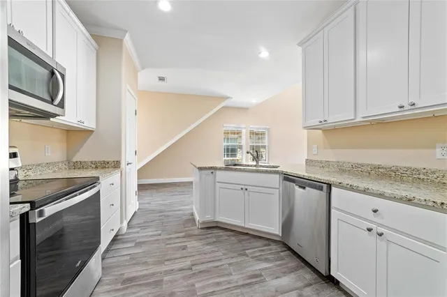 a kitchen with granite countertop cabinets stainless steel appliances a sink and wooden floor