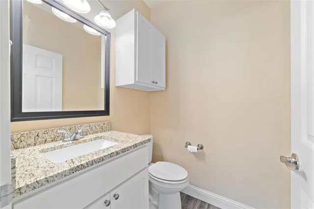 a bathroom with a granite countertop sink a toilet and a mirror