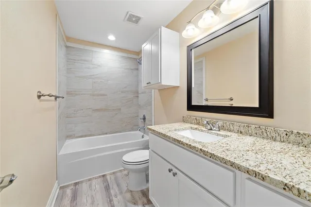 a bathroom with a granite countertop sink toilet and shower