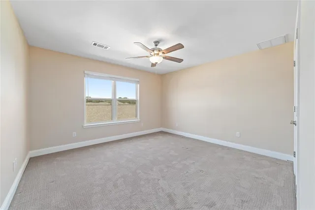an empty room with windows and ceiling fan