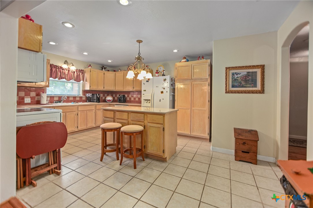 218 Burnet Street Port Lavaca, TX 77979 - Photo 7 of 23 a kitchen with stainless steel appliances granite countertop a stove top oven a refrigerator a dining table and chairs with wooden floor