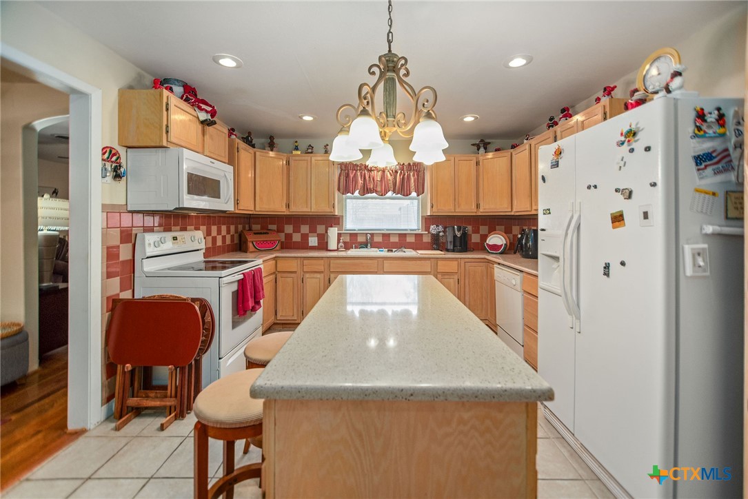 218 Burnet Street Port Lavaca, TX 77979 - Photo 8 of 23 a kitchen with stainless steel appliances granite countertop a refrigerator a sink dishwasher a dining table and chairs with wooden floor