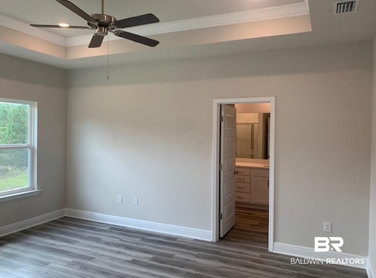 12904 Grand Rpds Road Fairhope, AL 36532 - Photo 23 of 34 Empty room with dark wood-type flooring, ceiling fan, and a tray ceiling