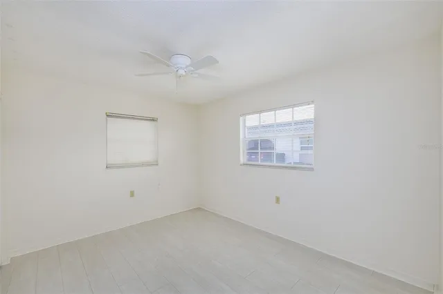 an empty room with a window and a fan