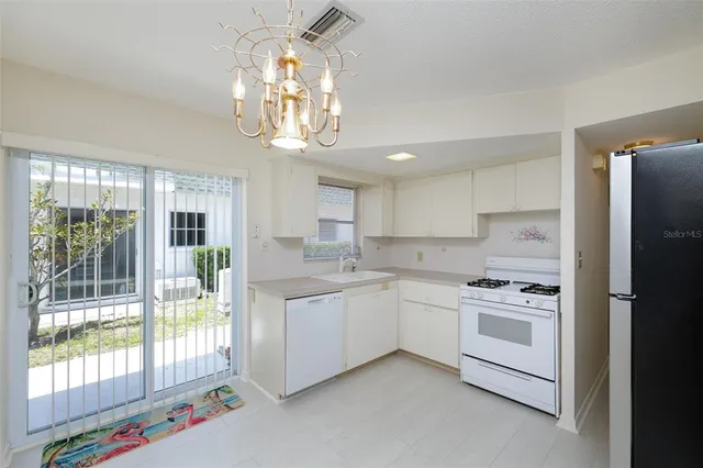 a kitchen that has a lot of white cabinets and stainless steel appliances