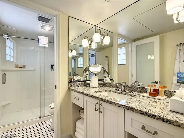 a bathroom with a granite countertop sink a mirror and shower