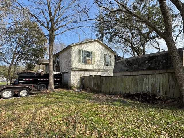 a view of a house with a large tree and wooden fence