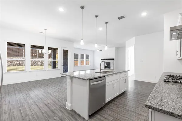 a kitchen with stainless steel appliances granite countertop a sink a stove and a wooden floors