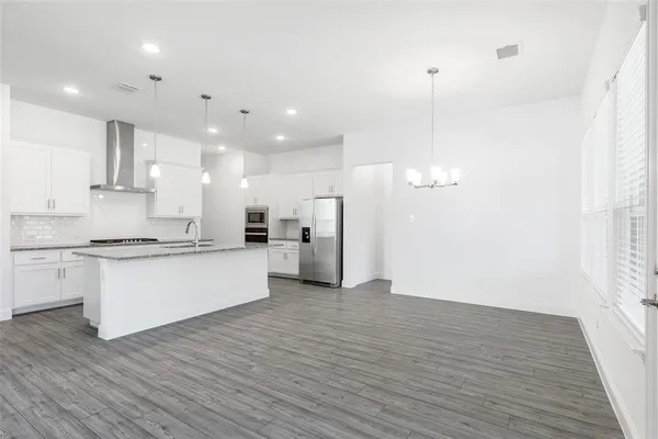 a large kitchen with granite countertop a white stove top oven and white cabinets