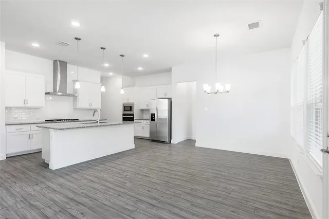 a large kitchen with granite countertop a white stove top oven and white cabinets