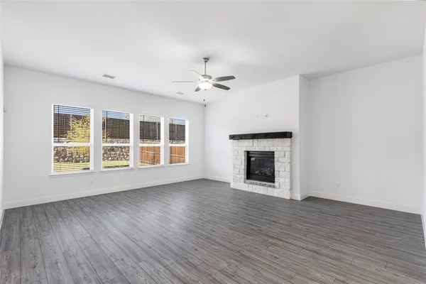 a view of an empty room with wooden floor fireplace and a window