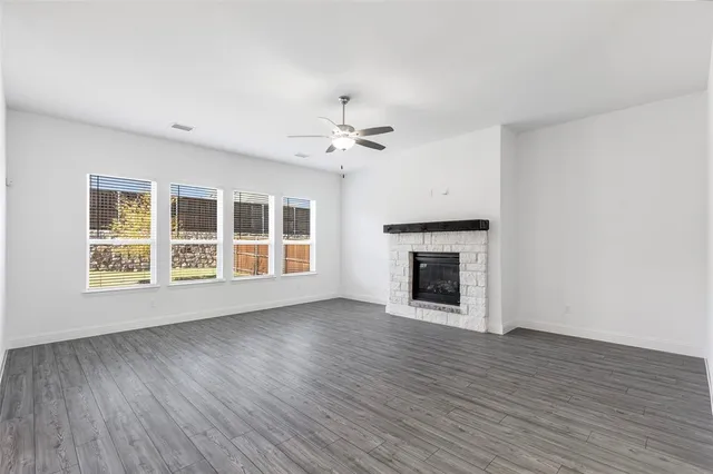 a view of an empty room with wooden floor fireplace and a window