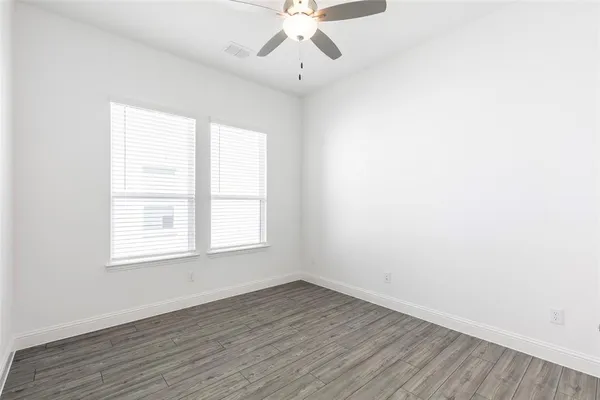 an empty room with wooden floor chandelier fan and window