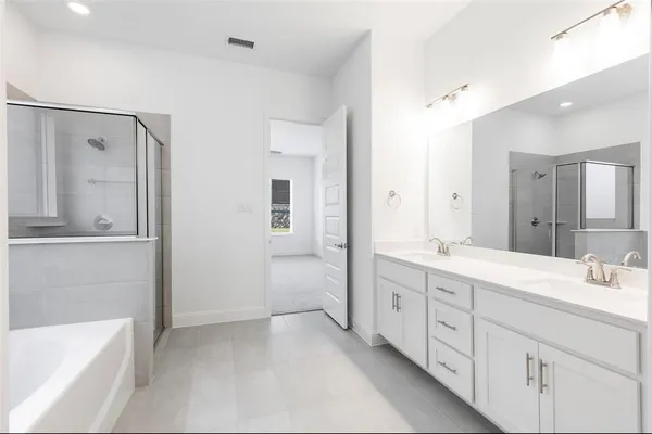 a spacious bathroom with a double vanity sink a mirror and a bathtub