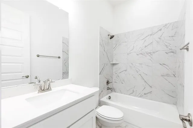 a bathroom with a granite countertop bathtub shower sink vanity mirror and toilet