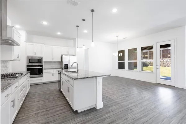 a large kitchen with stainless steel appliances granite countertop a stove a sink and a wooden floors