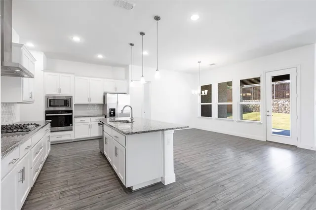 a large kitchen with stainless steel appliances granite countertop a stove a sink and a wooden floors