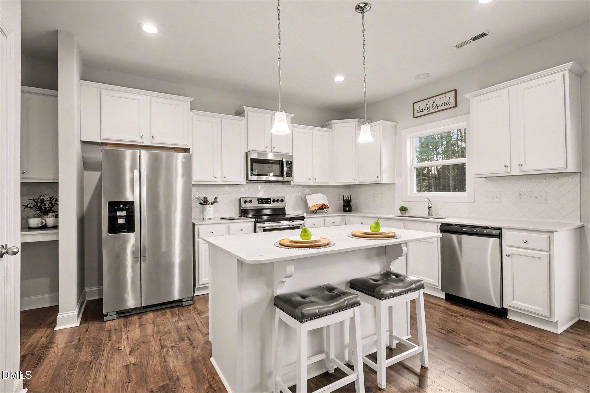 190 Stephens Timberline View Clayton, NC 27520 - Photo 16 of 42 a kitchen with stainless steel appliances a stove a sink a refrigerator and white cabinets with wooden floor