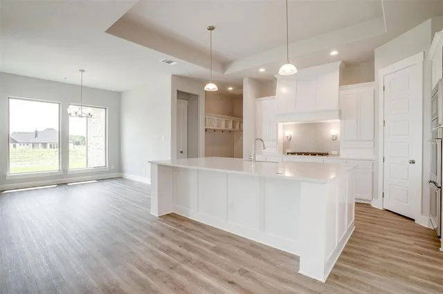 a large white kitchen with a large window a oven and wooden floor