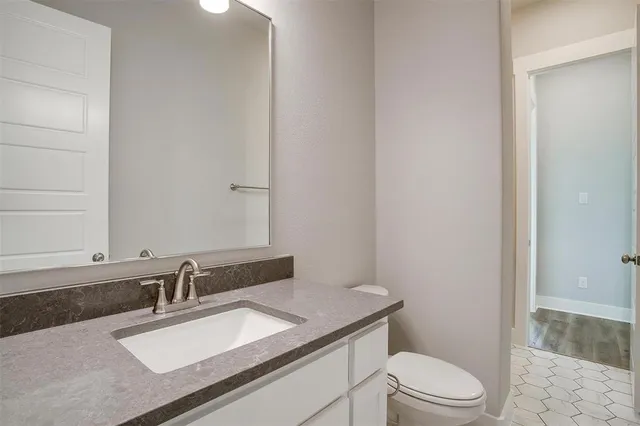 a bathroom with a granite countertop sink a toilet a mirror and shower