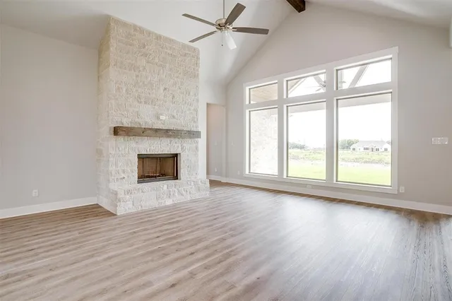 an empty room with wooden floor fireplace and windows