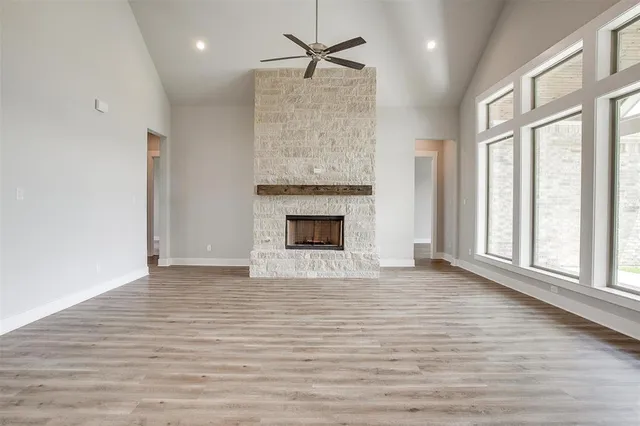 an empty room with wooden floor a fireplace and windows