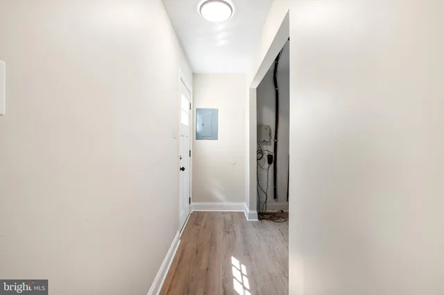 a view of a hallway with wooden floor and a bathroom