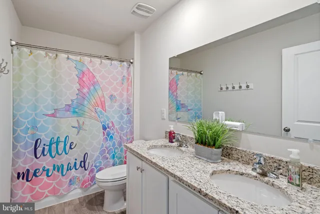 a bathroom with a granite countertop sink mirror vanity and toilet